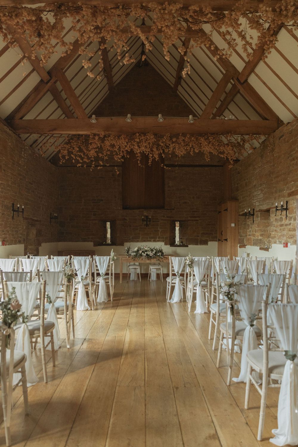 Rustic barn wedding venue with exposed wooden beams and rows of white chairs set up for a ceremony.