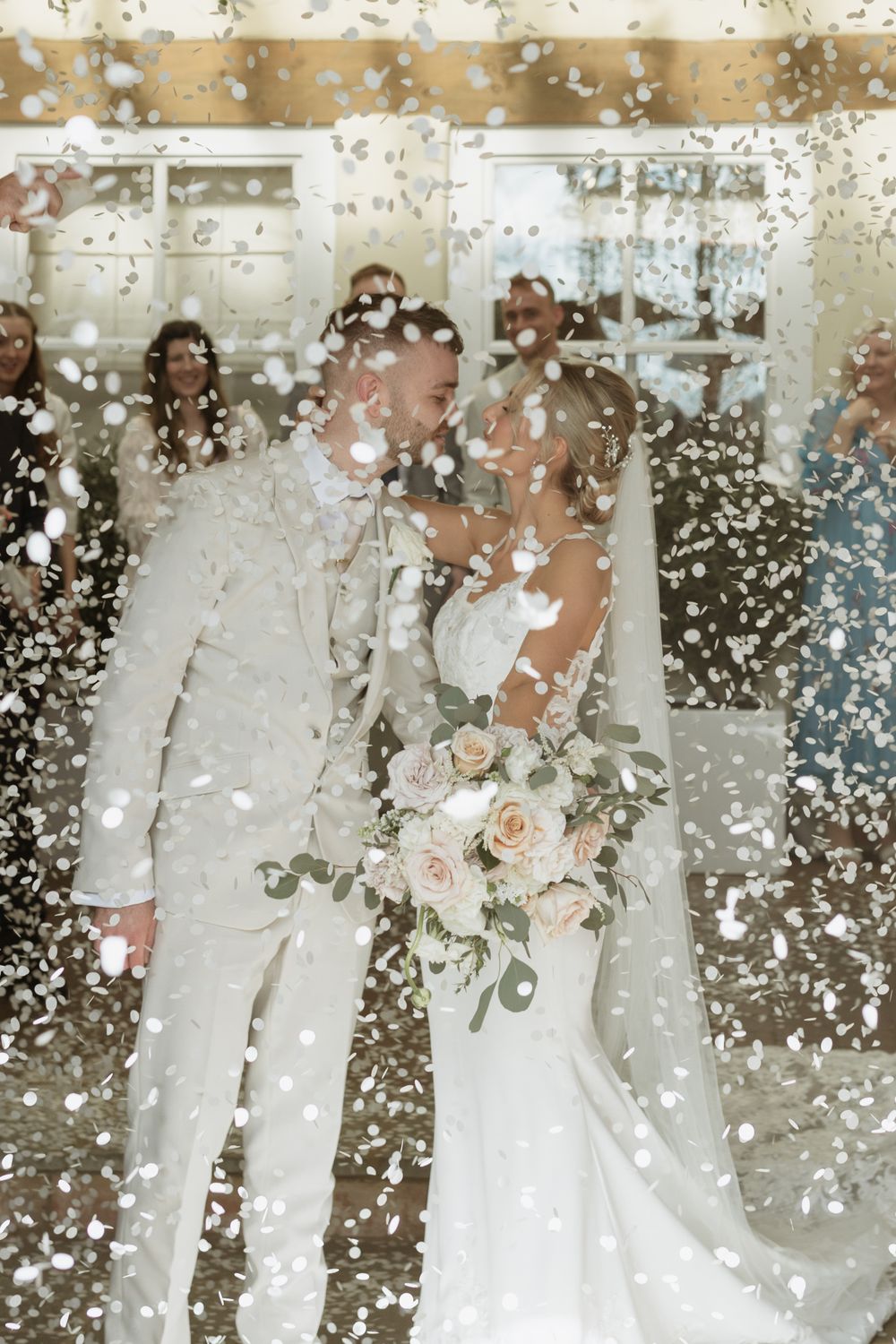 Wedding celebration with confetti falling around couple in elegant white attire dancing at reception.