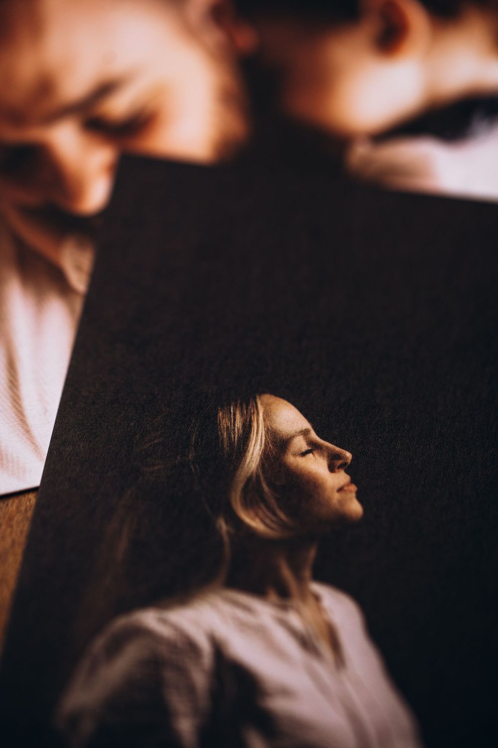 A moody artistic portrait in profile view showing someone with blonde hair against a dark background.