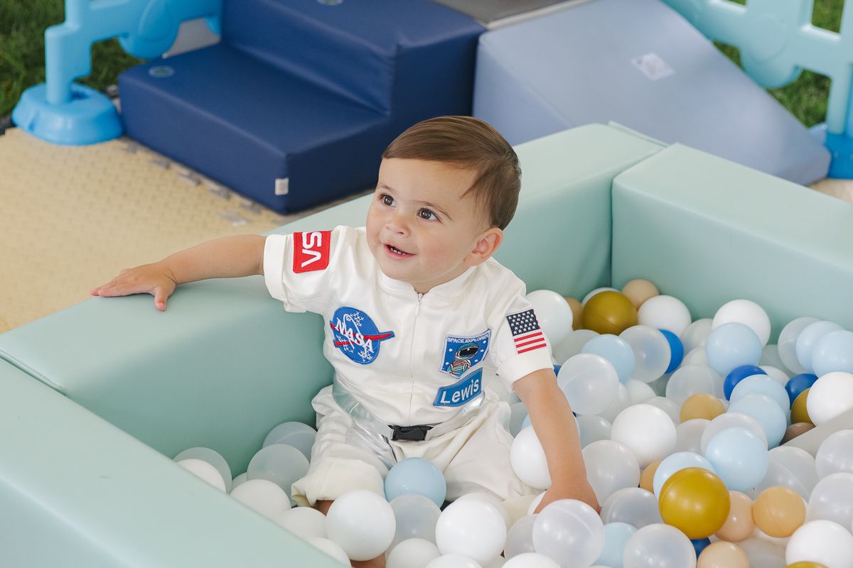 Excited birthday boy playing in a vibrant ball pit during his space-themed first birthday celebration in Manhasset.