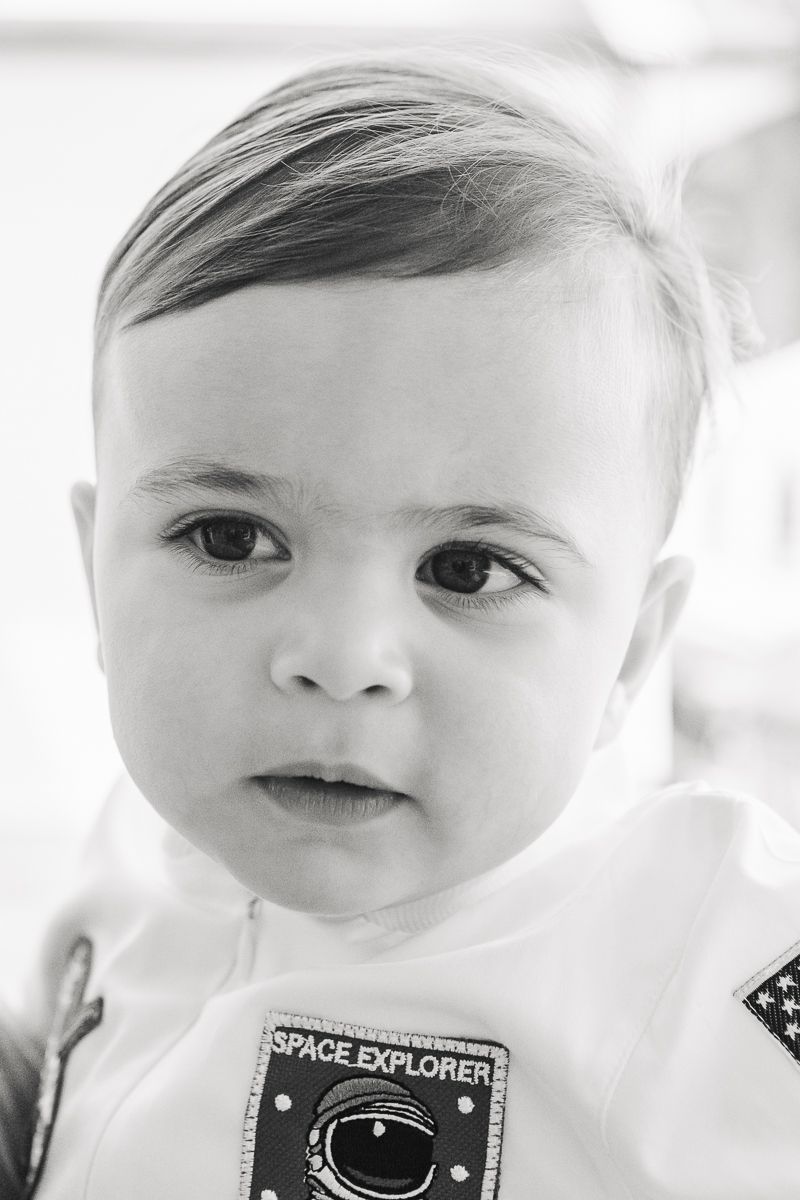 Smiling baby boy in a candid first birthday portrait, highlighting his excitement and personality