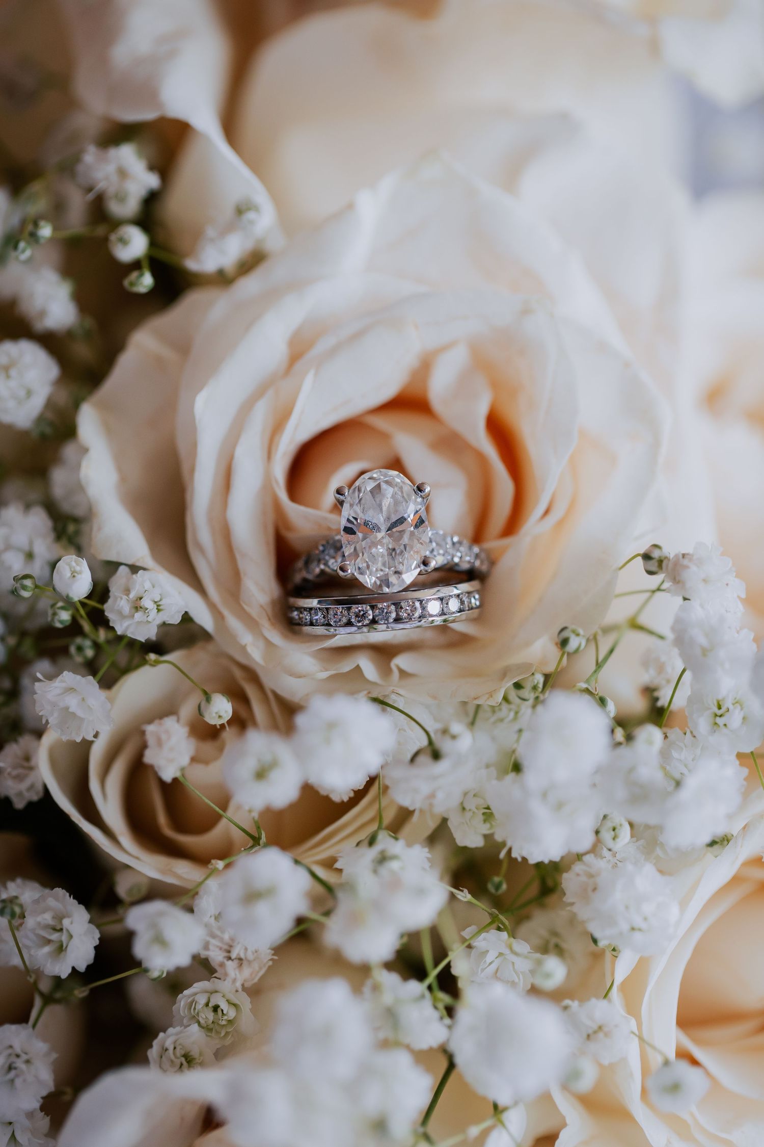Close-up detail shot of the bride’s engagement and wedding rings placed delicately in her bouquet, showcasing the intricate design.