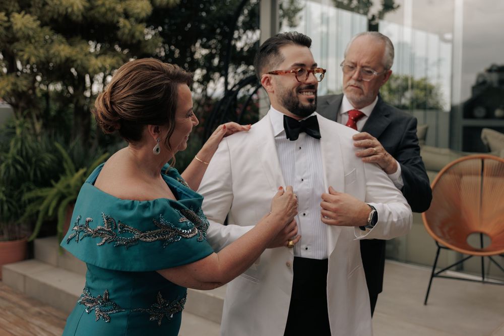 Three people gather on an outdoor patio sharing a moment during a formal celebration.