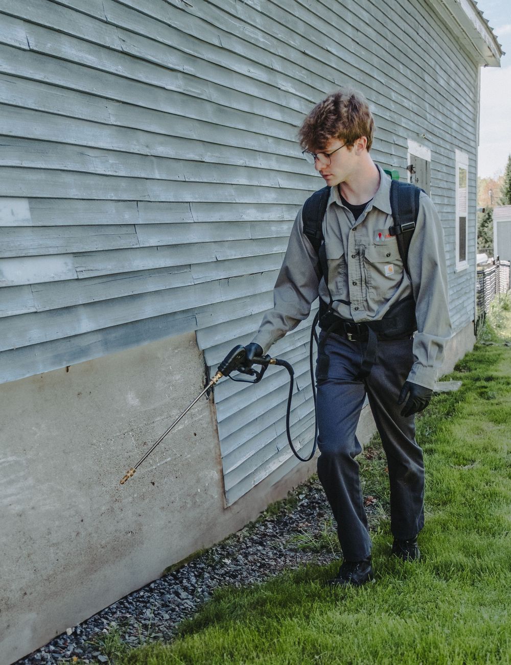 A Modern Pest Control Tech sprays the foundation of a home to prevent un-wanted critters from getting into the home.