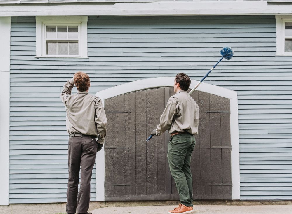Two Modern Pest Control Techs inspect the exterior of a large shed to ensure all cobwebs and hives have been removed appropriately.