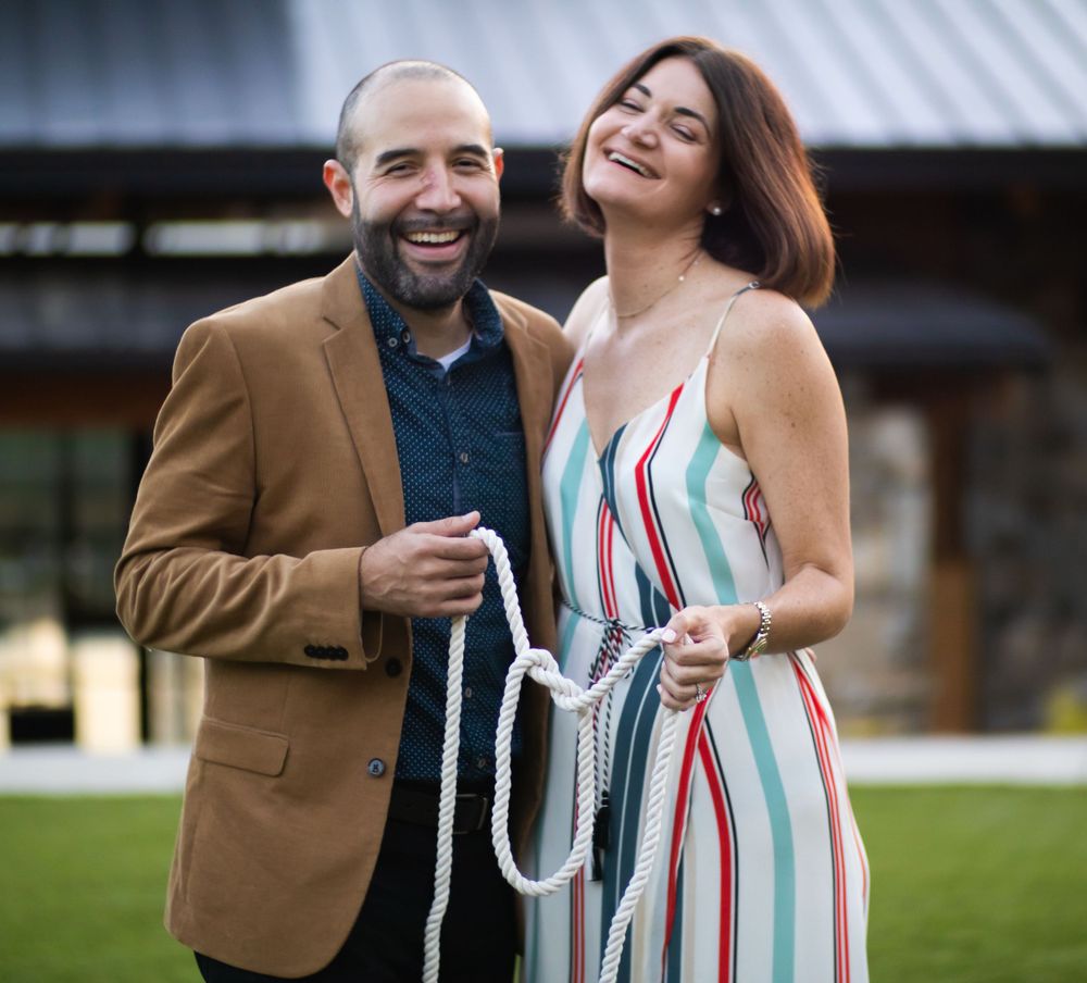 A happy couple laughs together outdoors while standing close to each other.