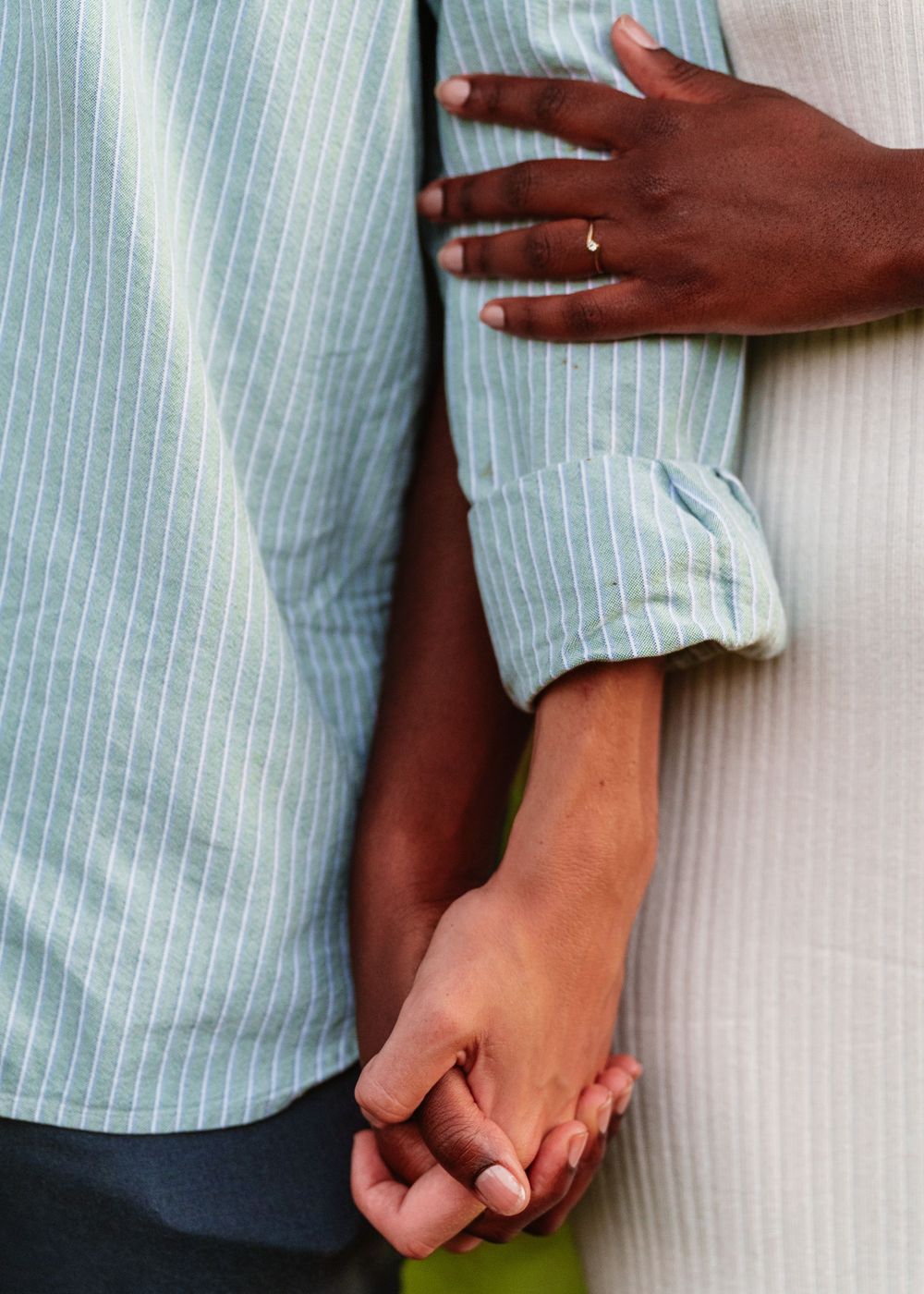 Close-up of hands holding each other against a striped shirt background.