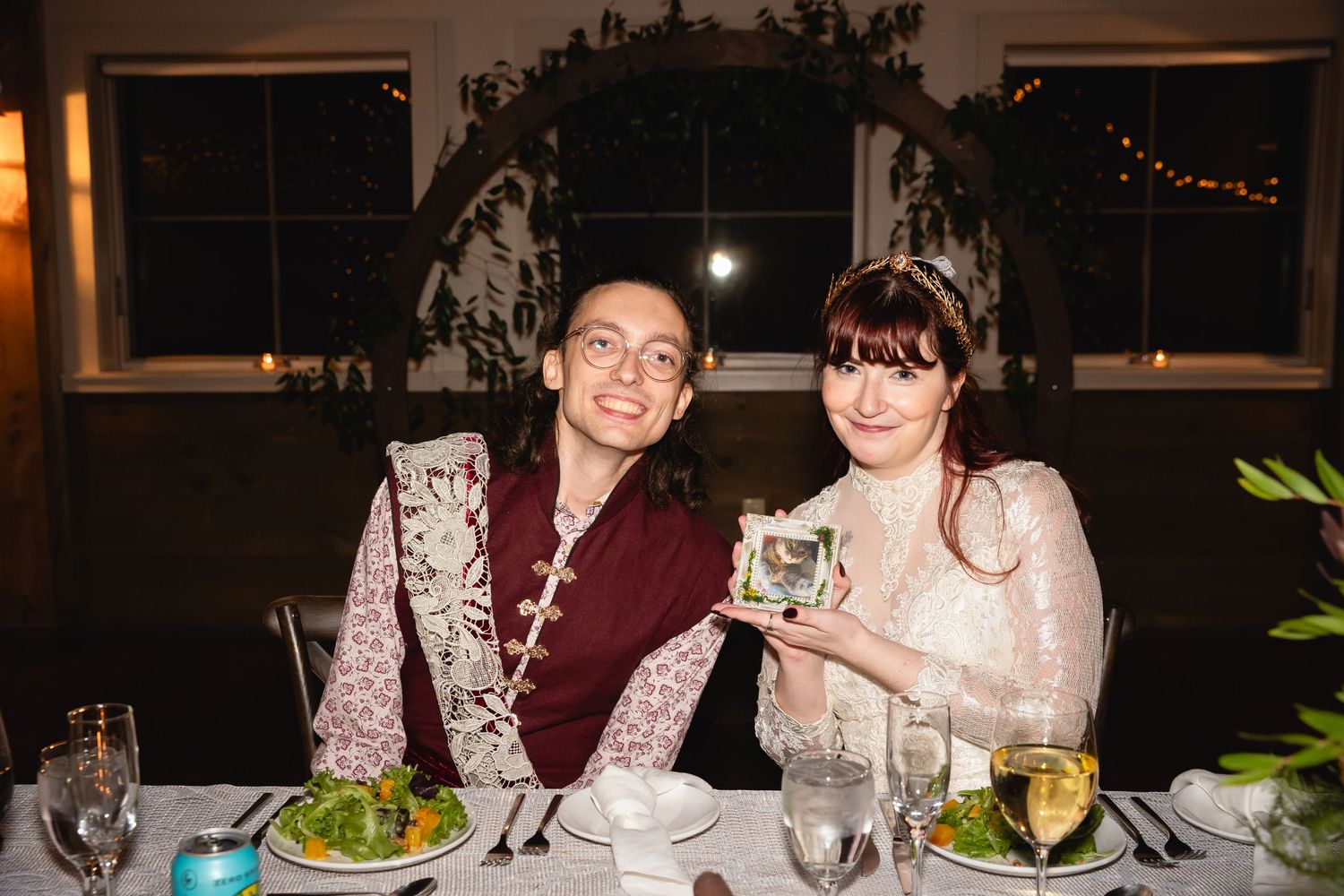 Two people at a dining table with decorative lighting and table settings enjoying a formal dinner together.