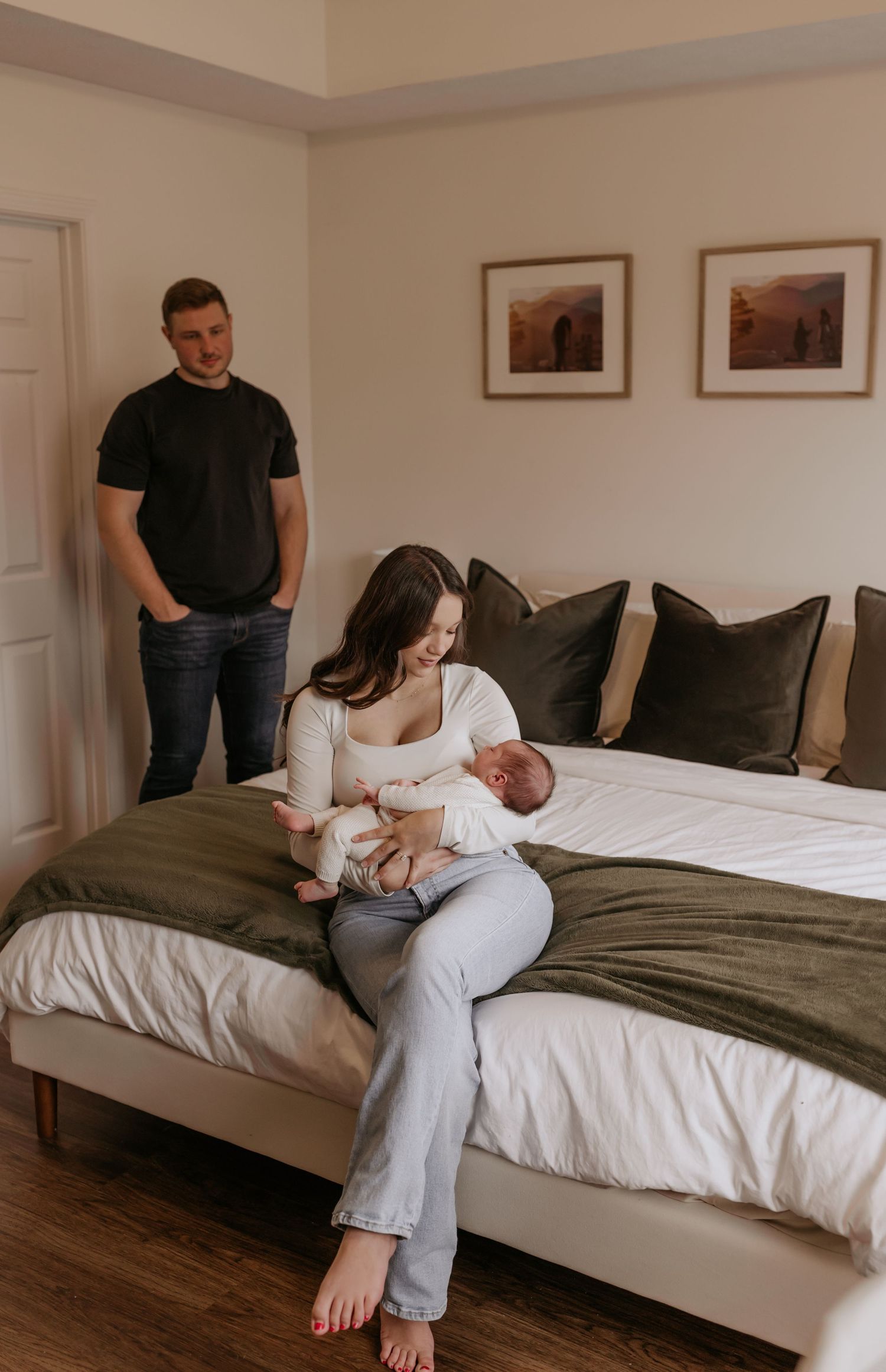 Black and white portrait of parents tenderly holding their sleeping newborn baby in a heartfelt outdoor family moment.