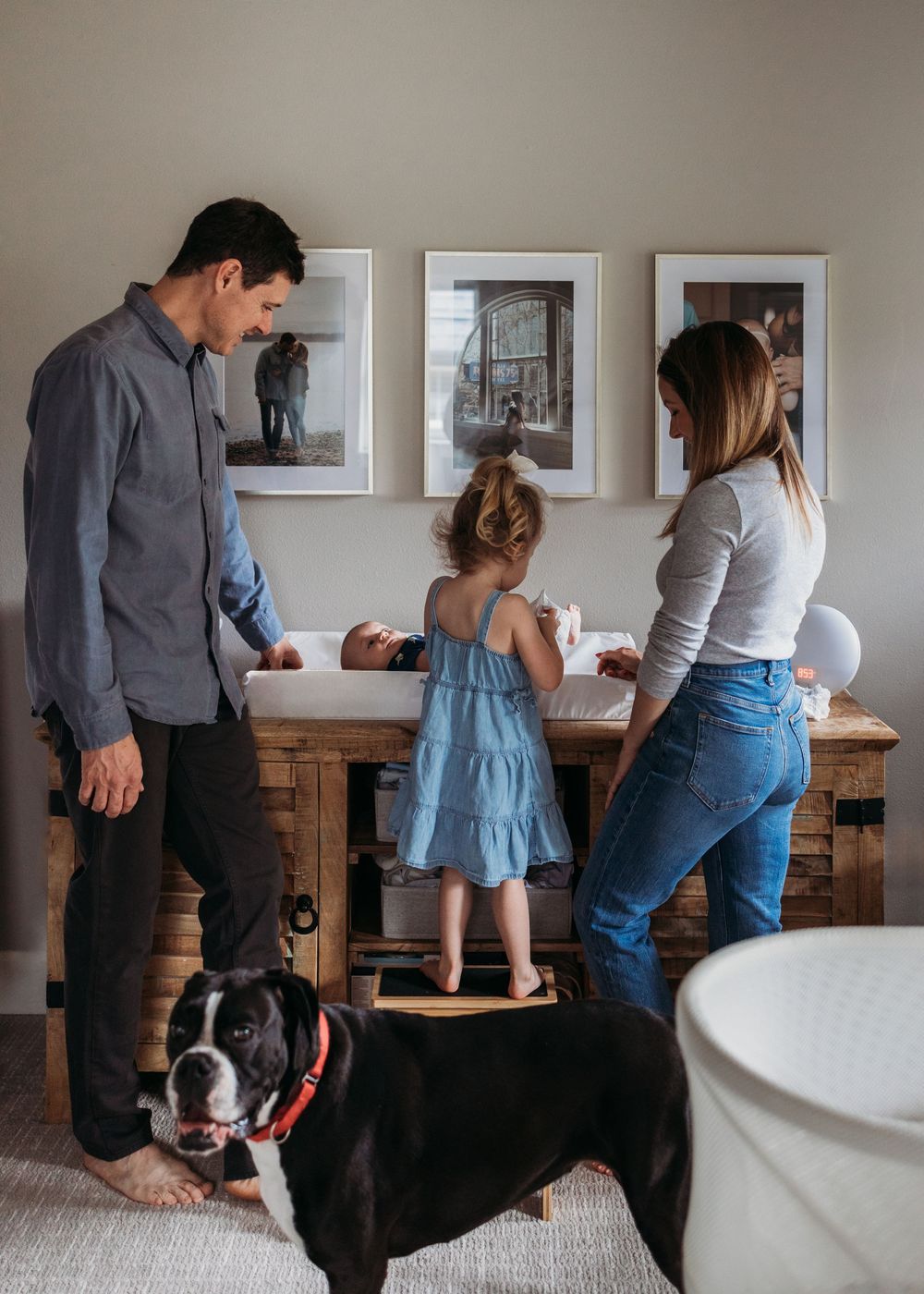 A small family spends time together in their dining room with their black and white Boston Terrier dog.