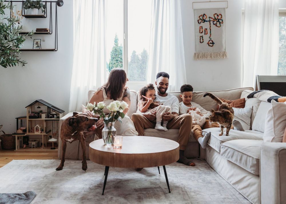 A family spending time together in their cozy living room with a round coffee table and plants by the window.