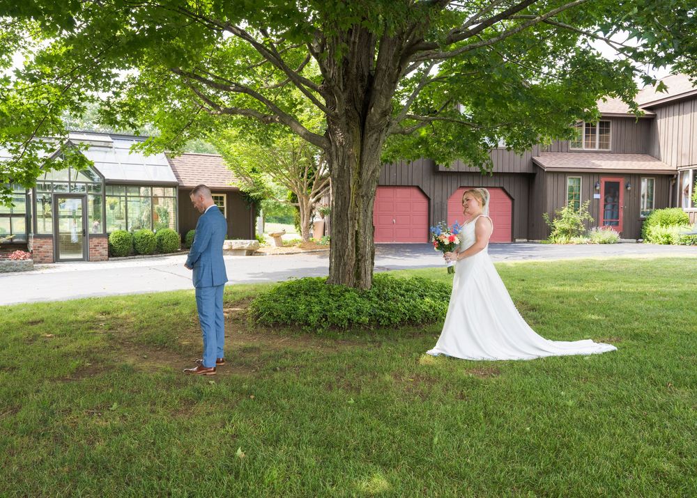 Wedding photos being captured under large shady trees on grassy lawn.