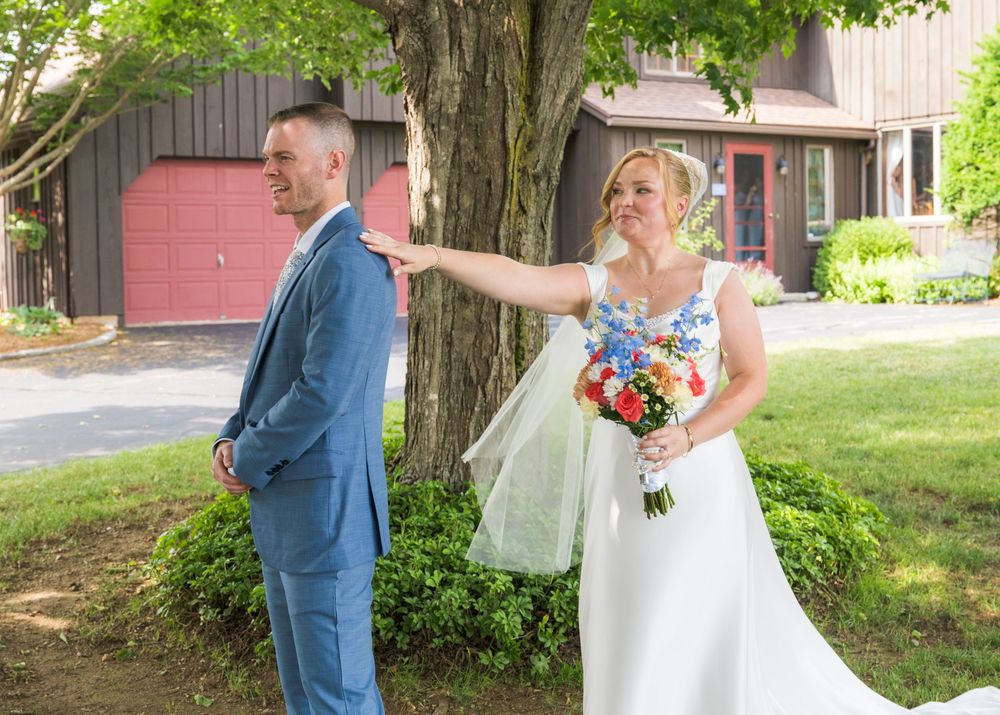 A couple shares their first look moment before their wedding ceremony in front of a pink garage door.