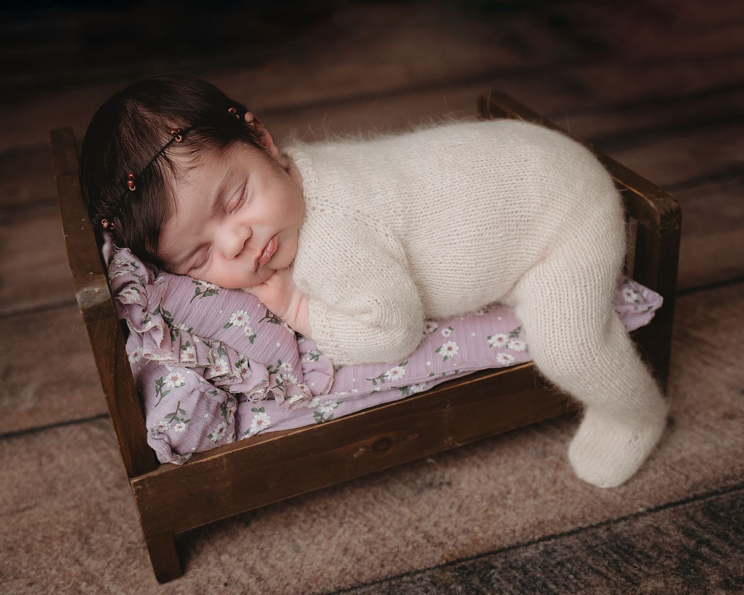 Professional photo of a newborn baby on a small bed sleeping