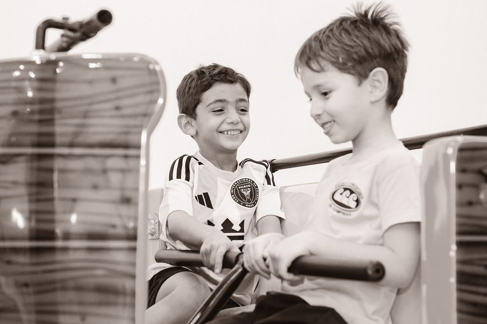 Two young children sit close together sharing a happy moment in black and white photography.