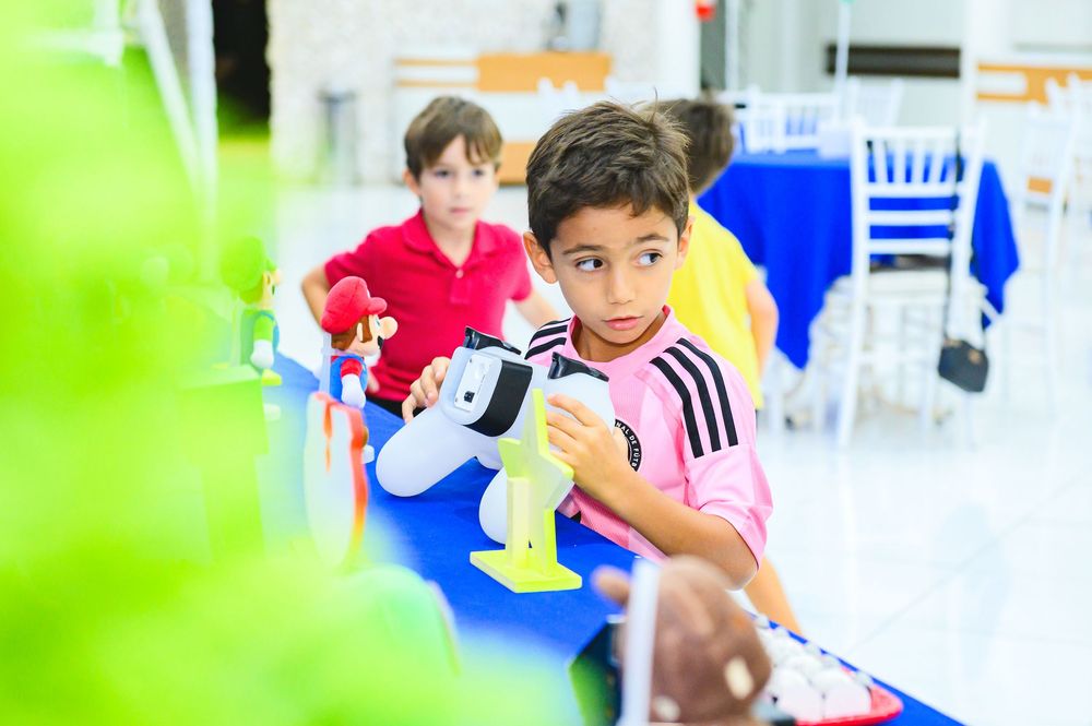 Children play indoors wearing athletic clothing during a sport or recreational activity at a bright facility.