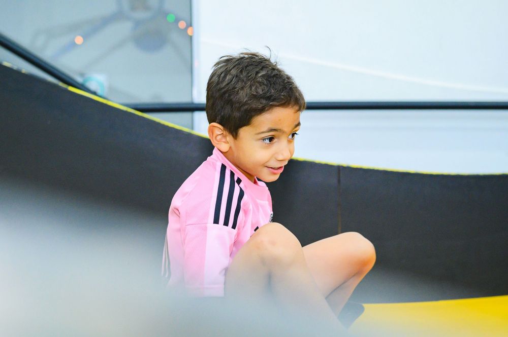 Young athlete in pink Adidas shirt sits alone during sports practice session.