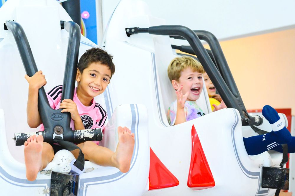 Two kids having fun exercising and playing on workout equipment at a fitness center.