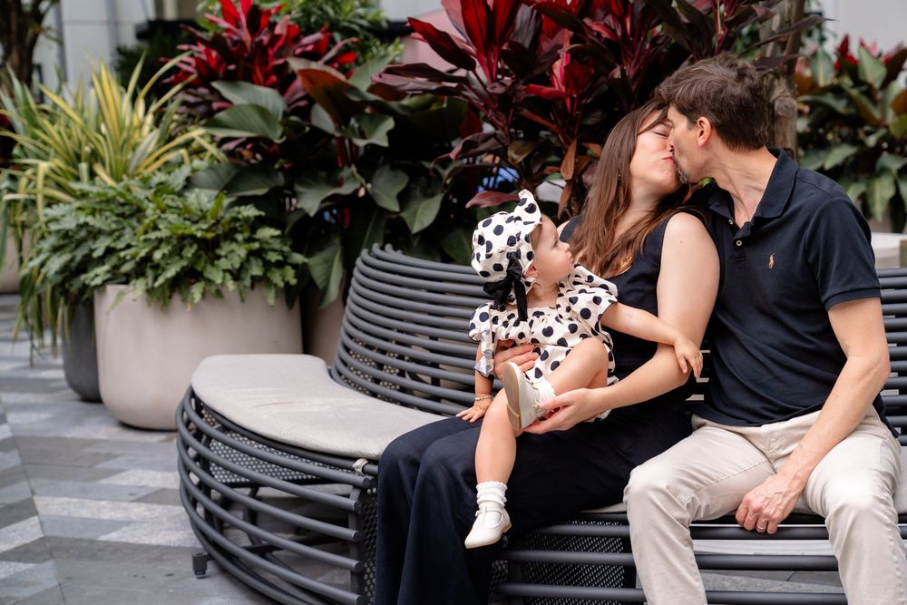 A tender moment shared on a bench surrounded by colorful tropical plants and modern architecture.