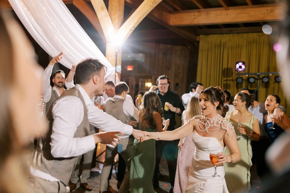 A joyful celebration of guests dancing with the newlyweds at a rustic barn wedding reception at Windham Manor.