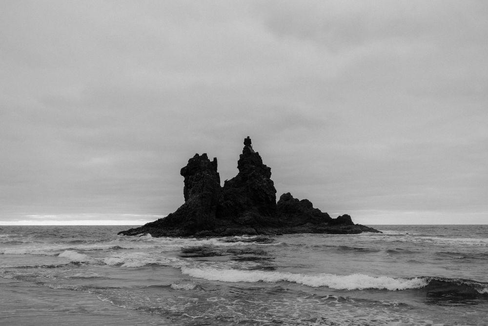 Dramatic black and white seascape featuring a rocky formation rising from turbulent waters captured at Playa de Benijo, North Tenerife.