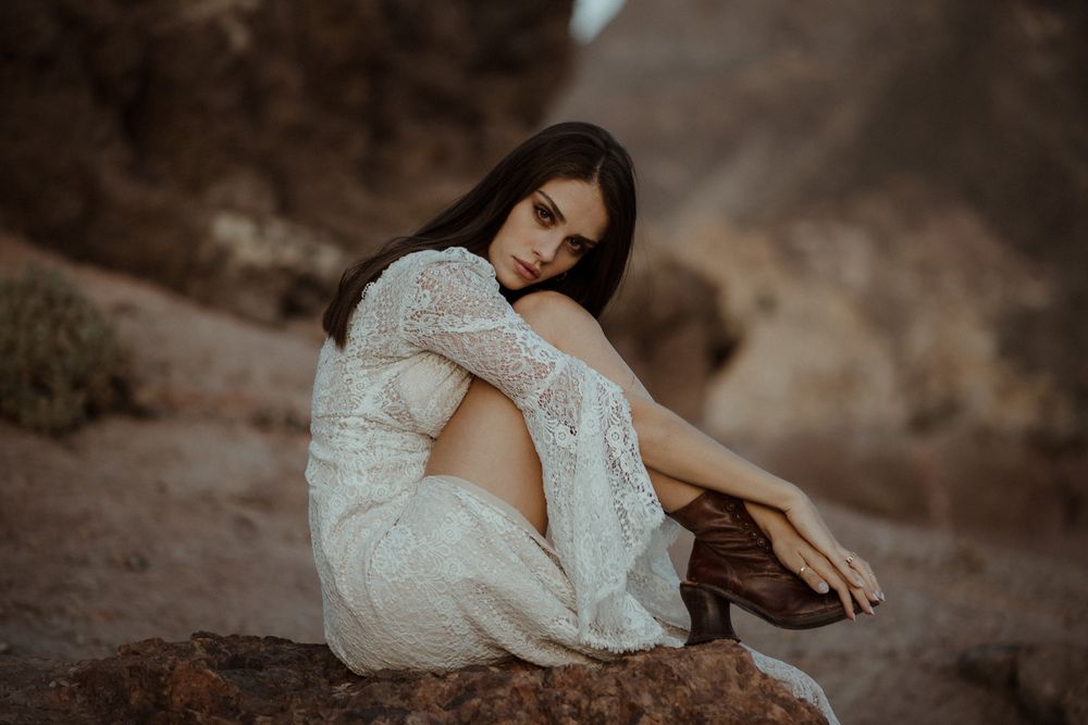Artistic bridal portrait on desert volcanic rocks in soft, muted tones.