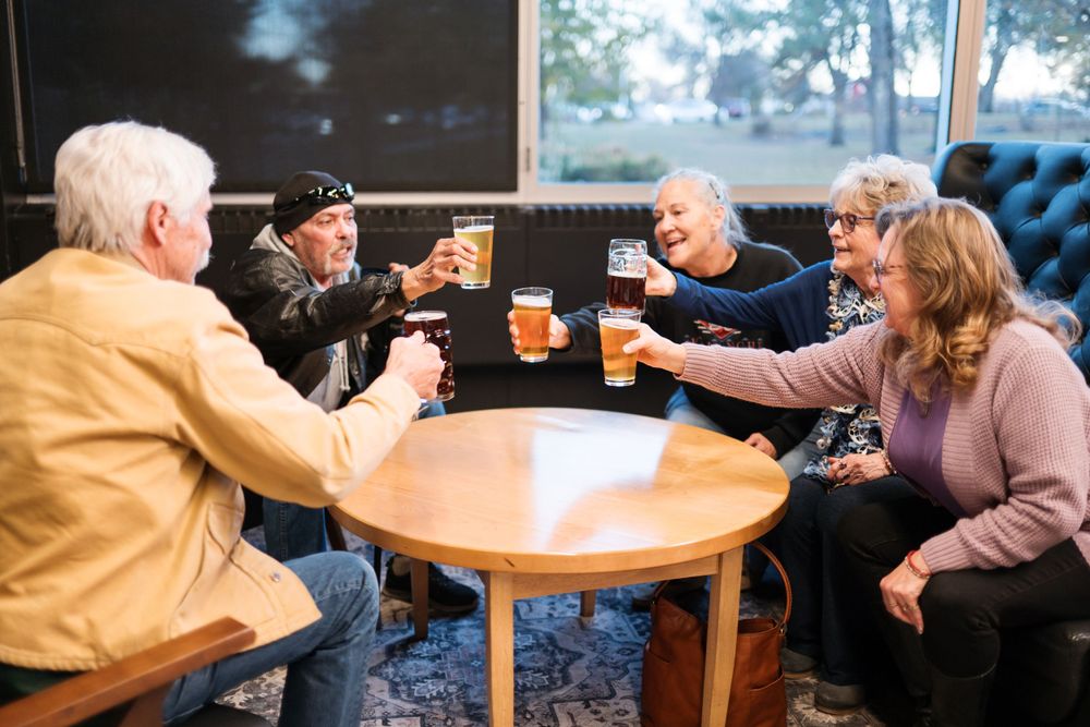 Friends enjoying drinks and conversation around a round table in a cozy pub setting.