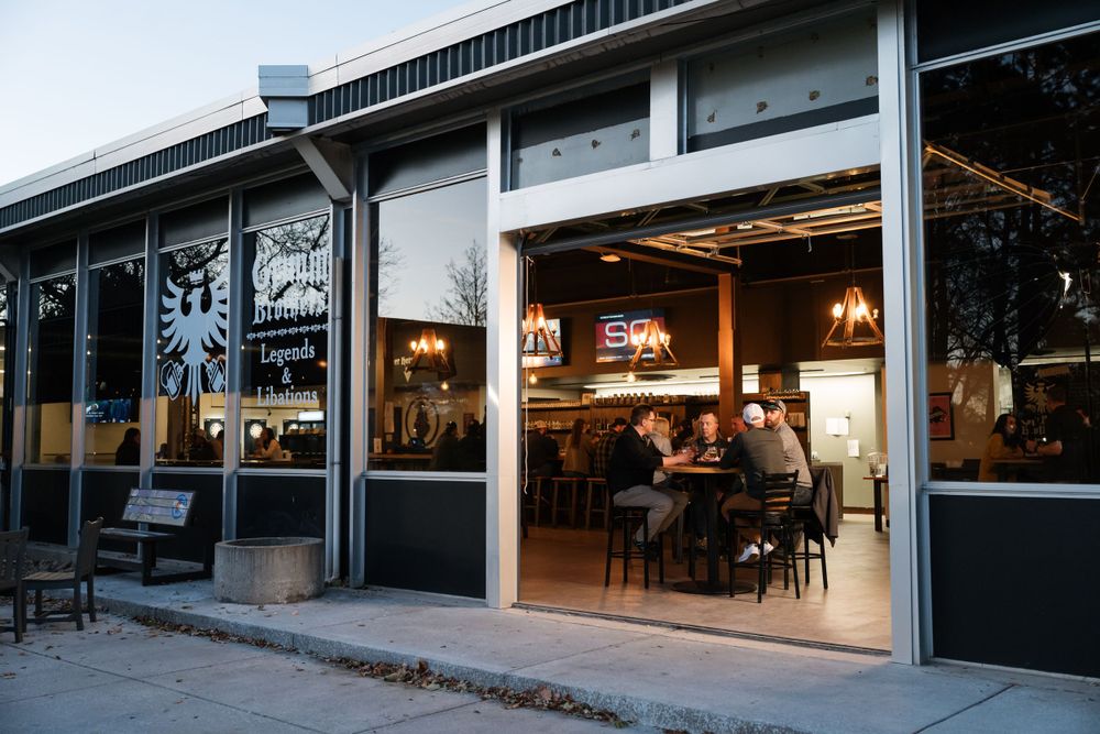Modern restaurant storefront with large windows and warm interior lighting at dusk.