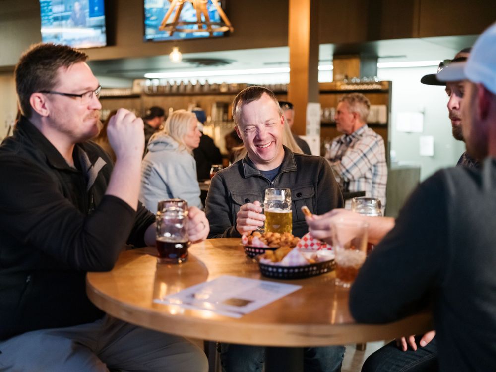 Friends sharing drinks and conversation at a round table in a pub.