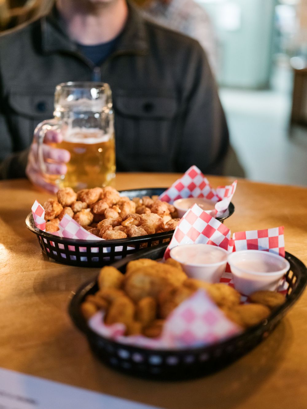 Fried appetizers and beer served in baskets with red checkered paper and dipping sauces.