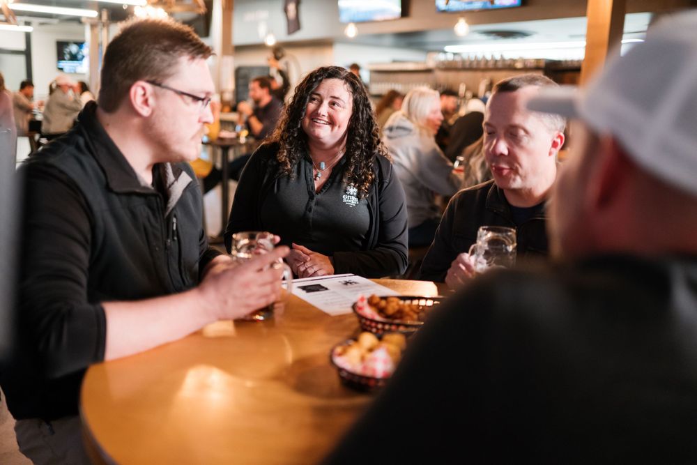A lively group enjoying food and drinks at a casual restaurant table.