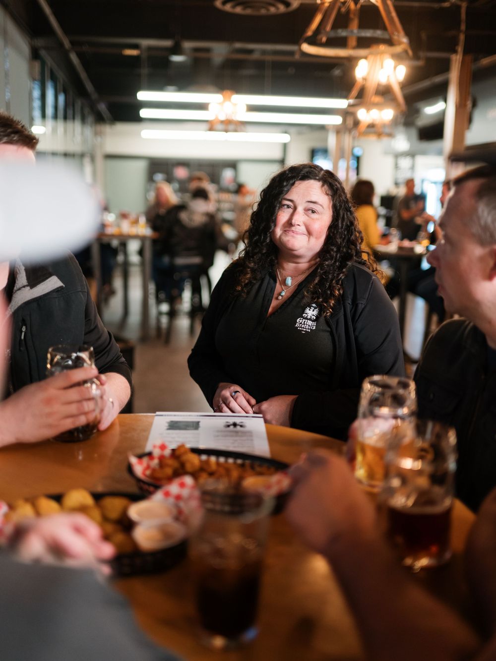 Diners enjoying conversation and drinks at a busy restaurant table.