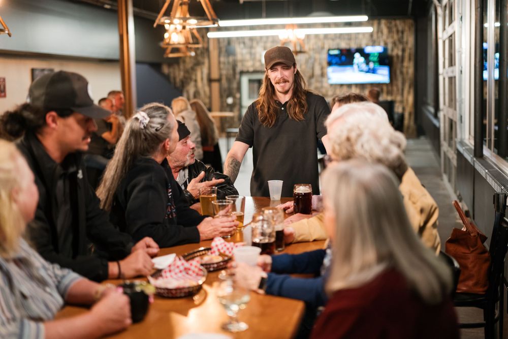 Server taking orders from customers at a busy restaurant table.