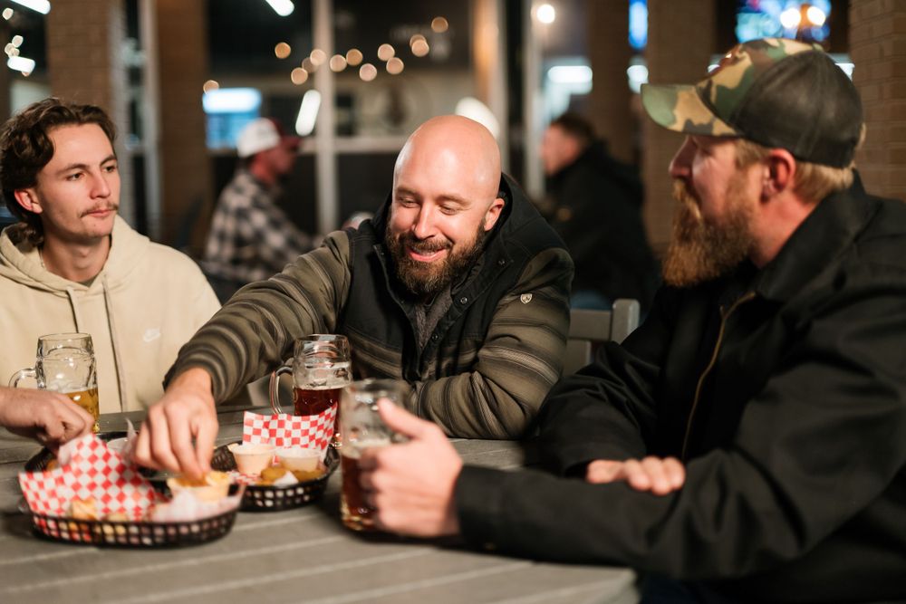 Three friends sharing drinks and conversation at a restaurant table.