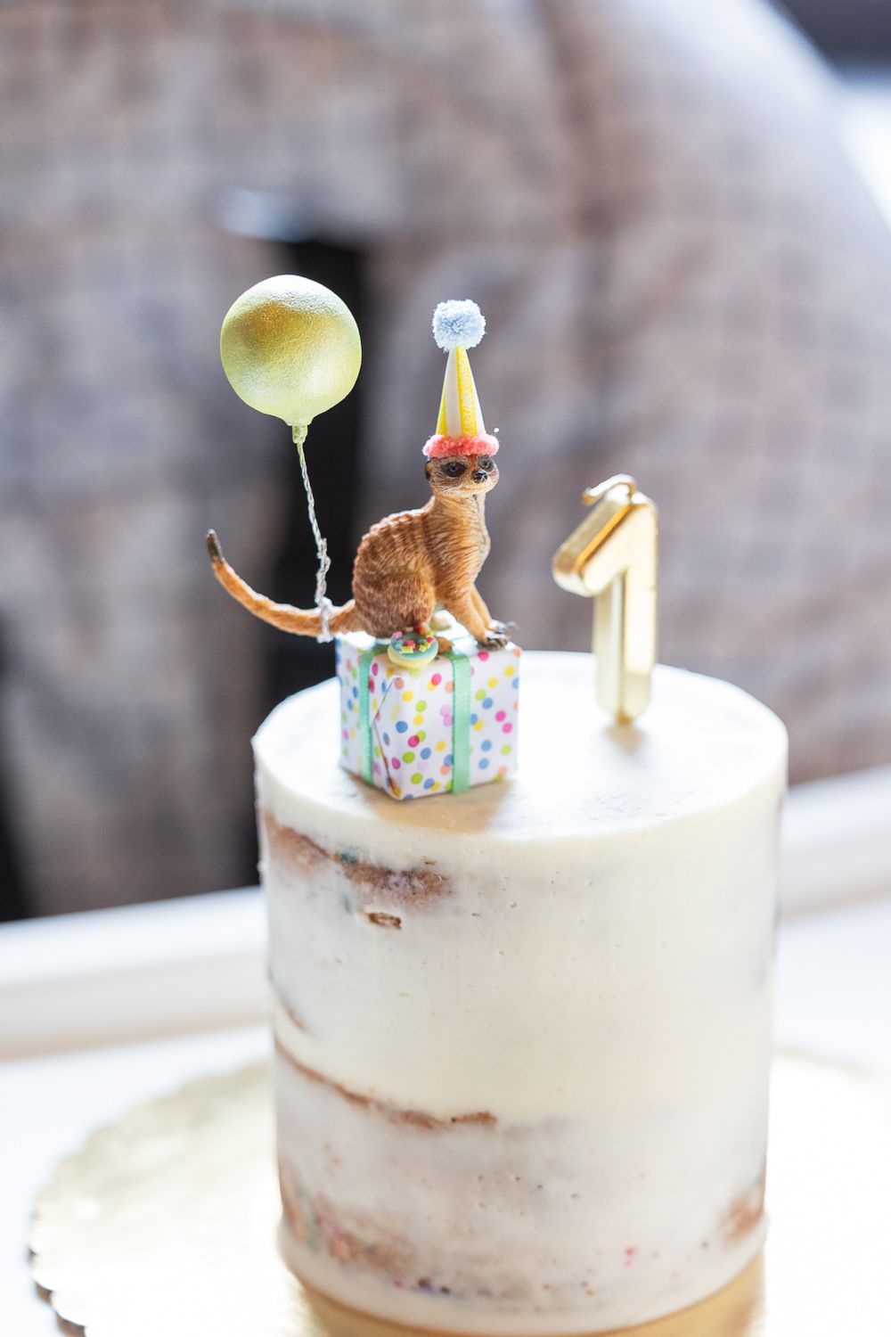 White semi-naked cake with gold number one and toy kangaroo topper.