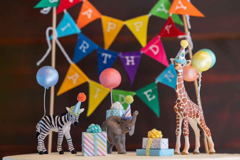 Safari themed birthday decor with toy animals and colorful bunting banner.