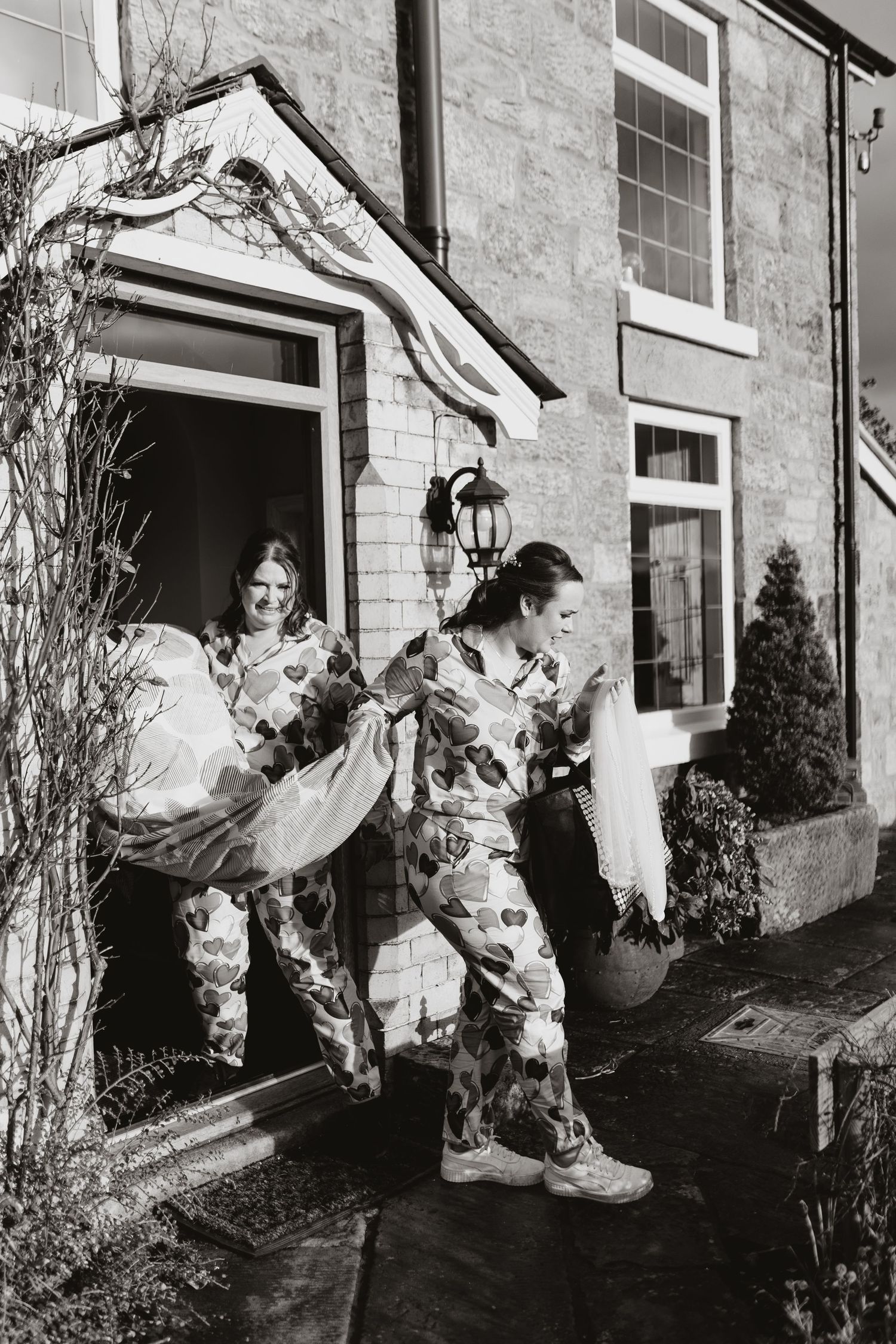 Black and white photo showing bridemaids carrying wedding dress for bride at Tower Hill Barn.