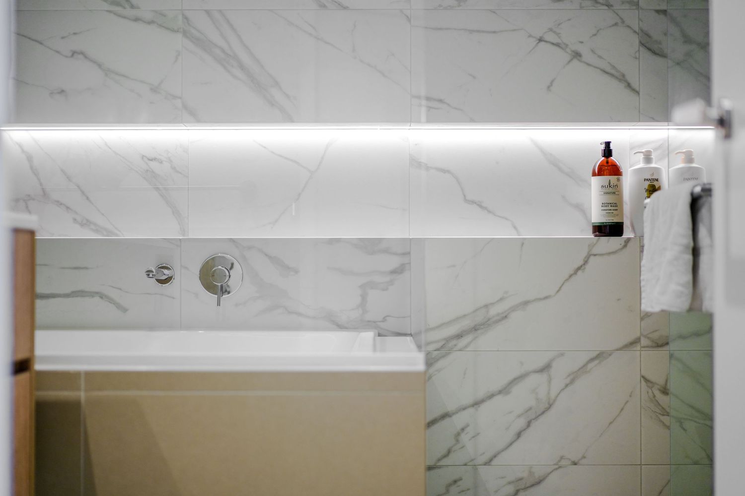 Modern bathroom interior featuring white marble walls and chrome fixtures with a minimalist design aesthetic.