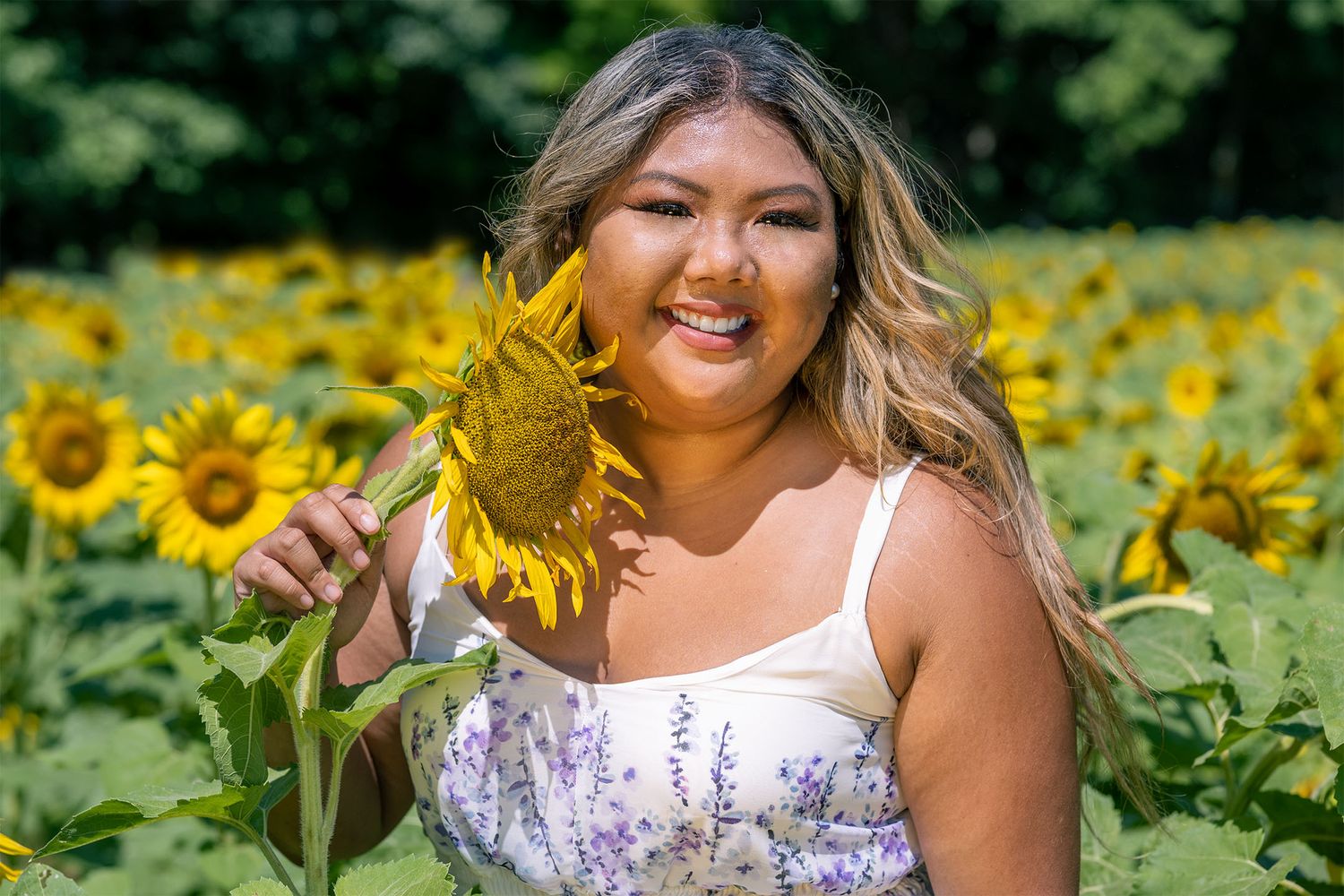 A girl posing with a sunflower during Sunflower Mini-Sessions