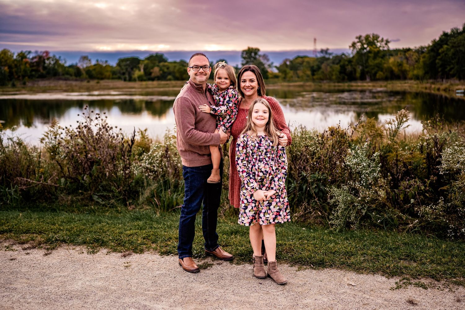 Sunset family photo by lake with fall foliage and dramatic sky.