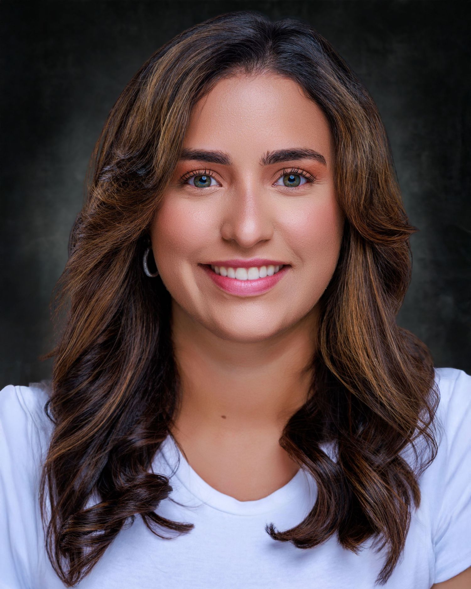 Professional headshot of a smiling woman with shoulder-length brown hair, wearing a blue blouse against a neutral background.