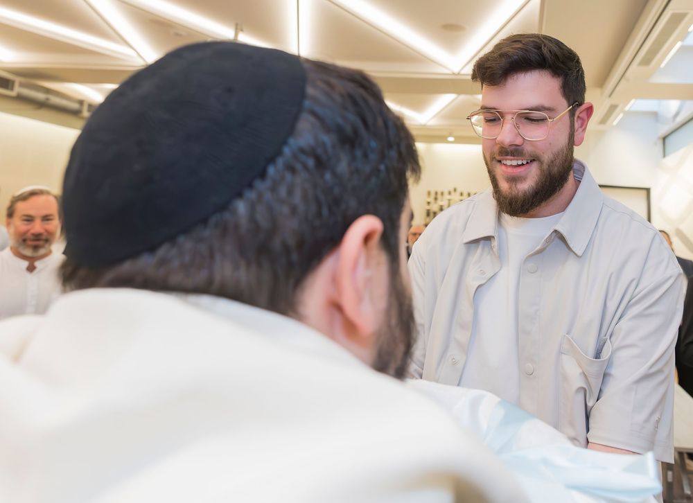 Two people having a conversation, one wearing a traditional Jewish yarmulke in an office setting.