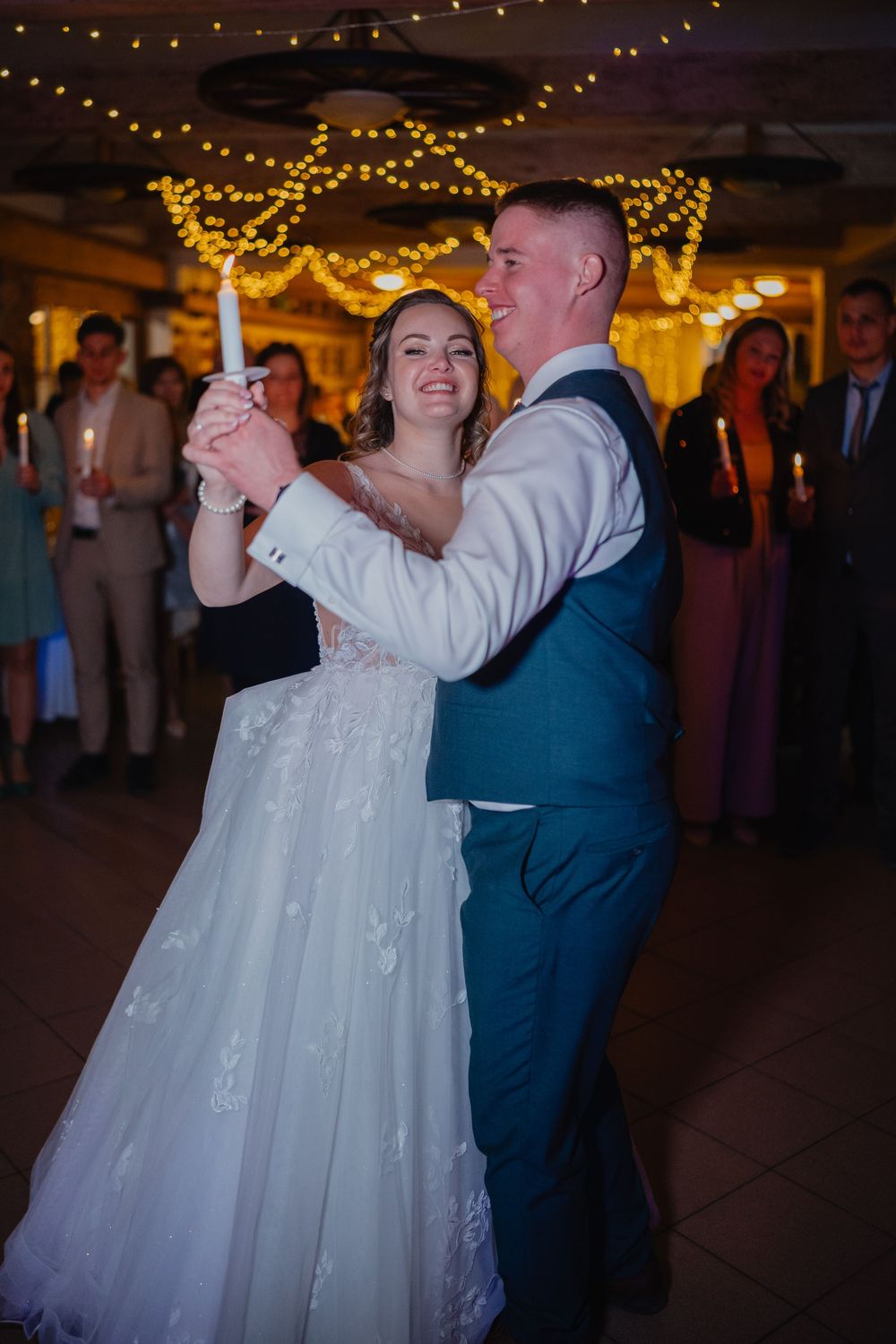 Couple shares their first dance at wedding reception under warm twinkle lights creating romantic ambiance.