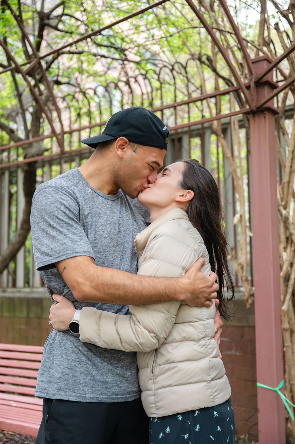 Romantic couple sharing an intimate kiss in the Westside Community Garden on the UWS during a proposal session