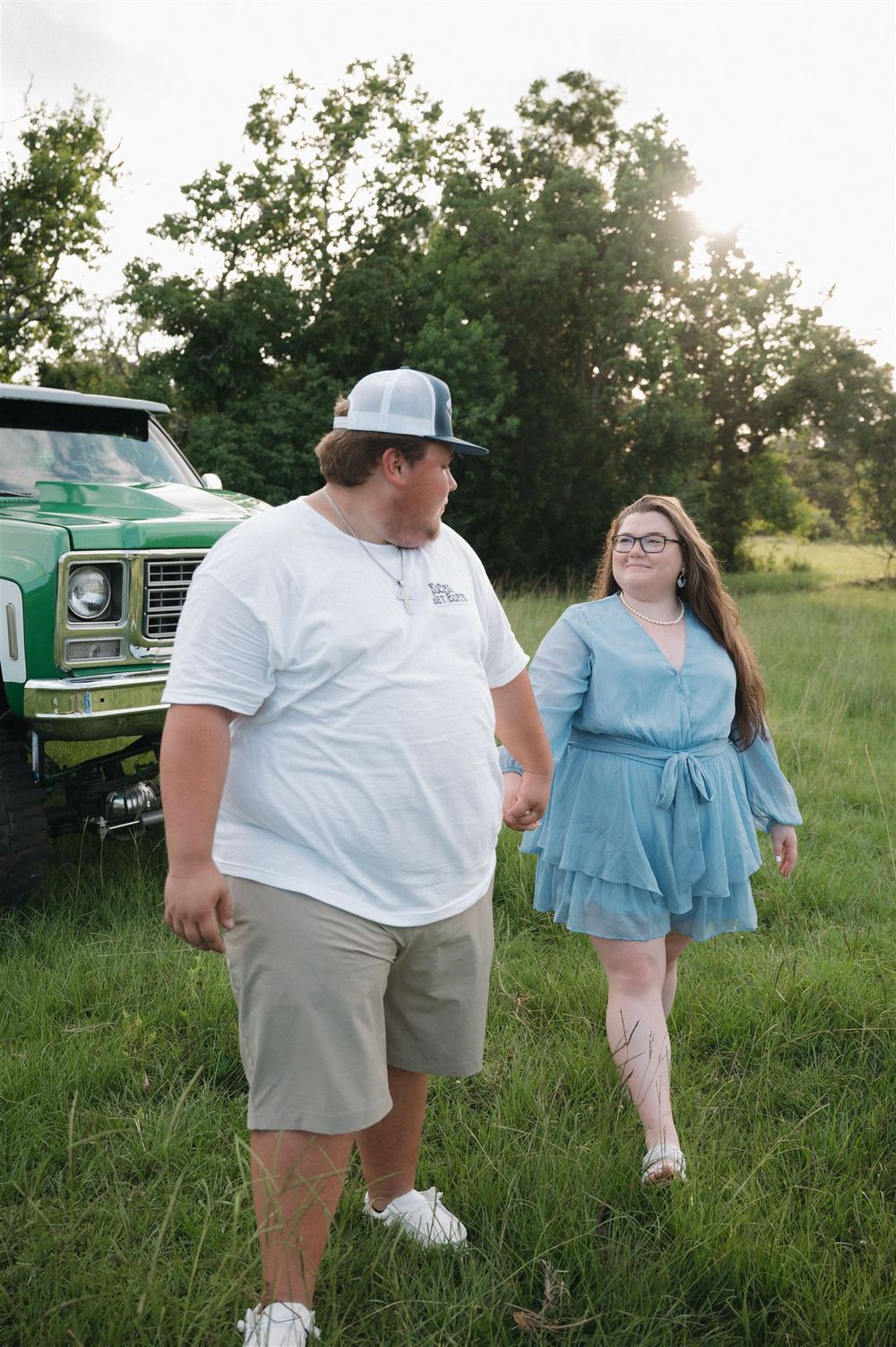 A sunny country scene with a vintage green truck parked in tall grass on a warm summer evening.
