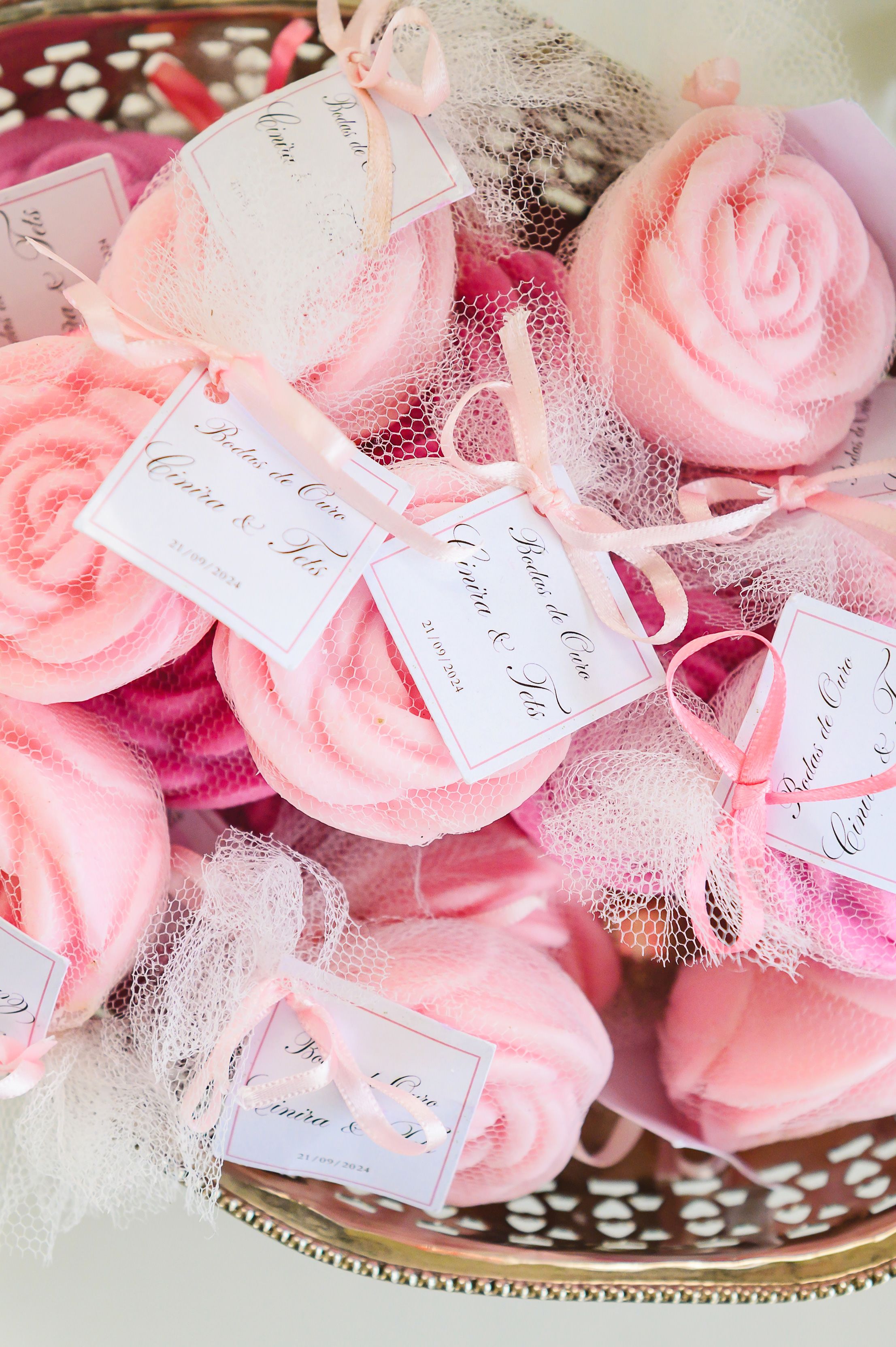 Delicate pink rose-shaped party favors with tulle and name tags arranged on a decorative silver tray.
