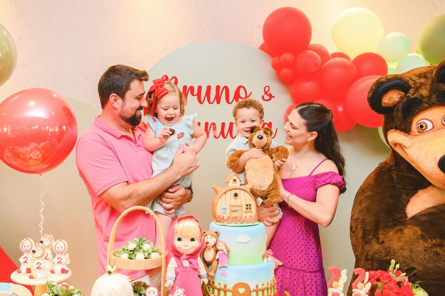 Festive birthday party scene with colorful balloons, birthday cake, and stuffed toys against decorated backdrop.