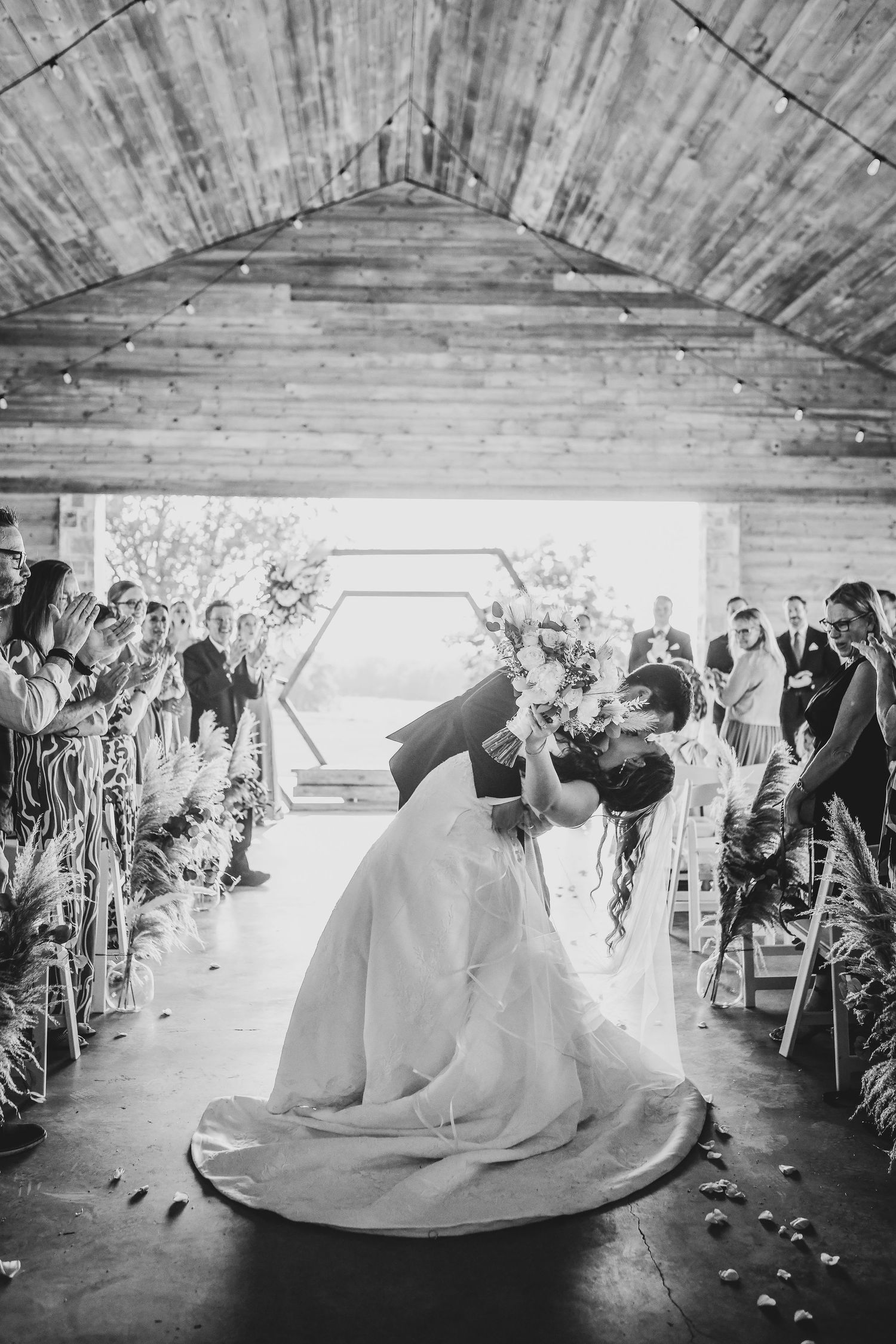 romantic black and white photo of bride and groom dipping and kissing after their wedding ceremony