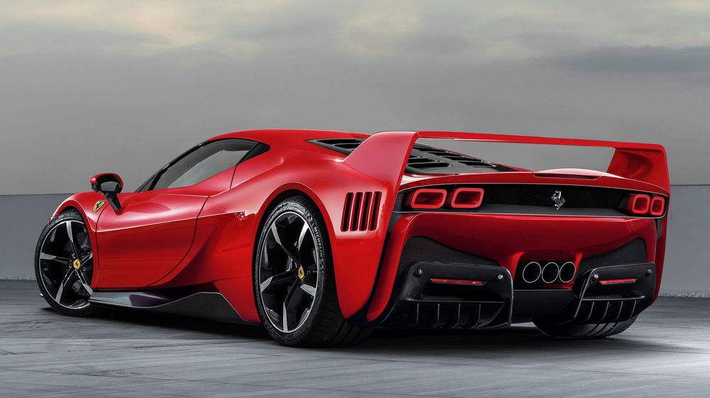 A sleek red Ferrari concept supercar with aggressive aerodynamics and black wheels against a moody cloudy backdrop.