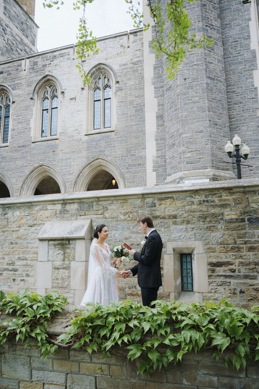 Bride and groom exchange moments on church terrace surrounded by Gothic architecture.